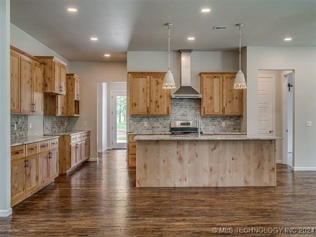 kitchen with a center island with sink, hanging light fixtures, wall chimney exhaust hood, and electric stove