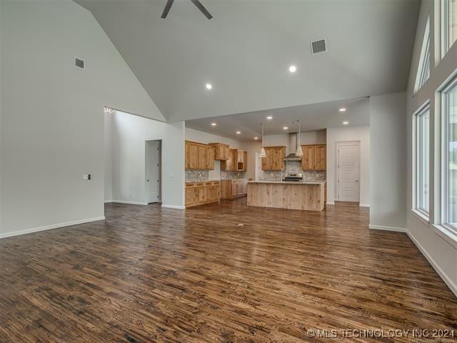 unfurnished living room with ceiling fan, high vaulted ceiling, and dark wood-type flooring