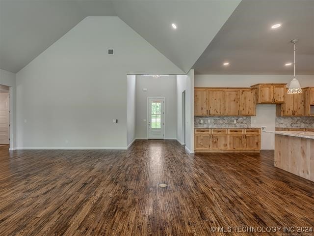 unfurnished living room with high vaulted ceiling and dark hardwood / wood-style floors