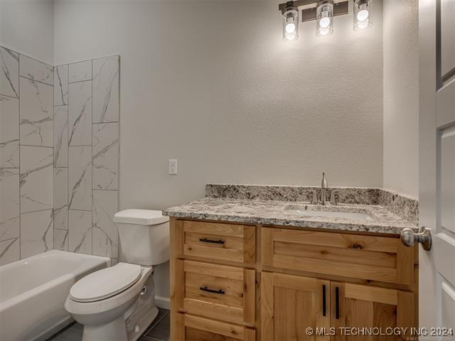 full bathroom featuring vanity, toilet, and tiled shower / bath