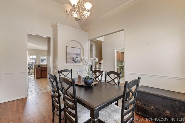 dining room featuring hardwood / wood-style floors, an inviting chandelier, crown molding, and vaulted ceiling