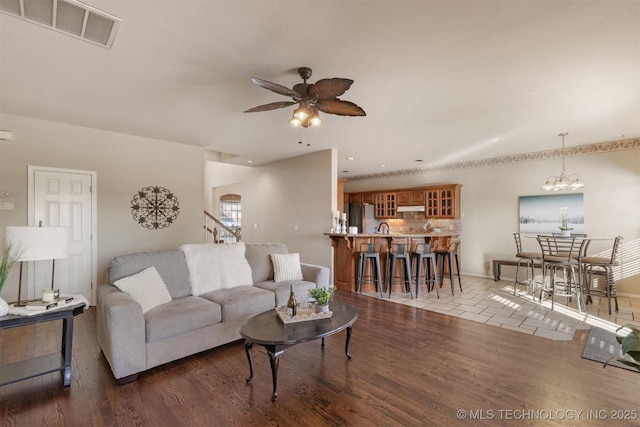 living room with dark hardwood / wood-style flooring, ceiling fan with notable chandelier, and sink