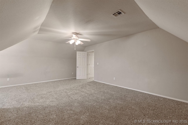 additional living space with carpet flooring, a textured ceiling, vaulted ceiling, and ceiling fan