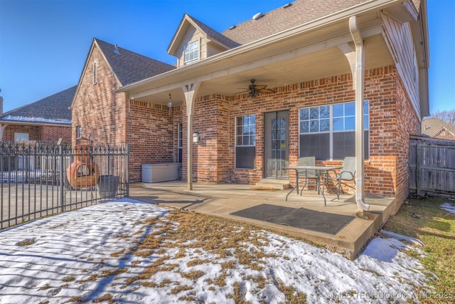 snow covered back of property featuring ceiling fan and a patio area