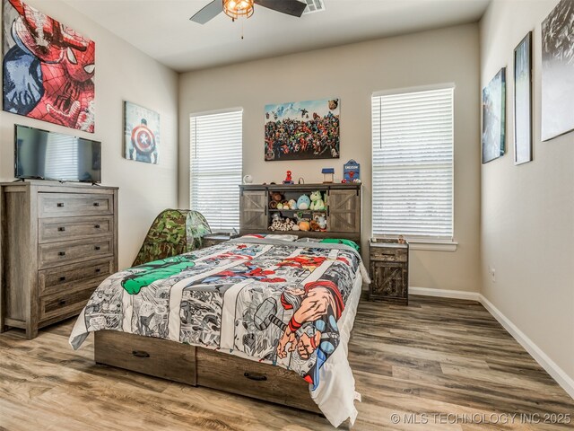 bedroom featuring ceiling fan, multiple windows, and hardwood / wood-style flooring