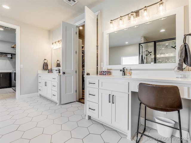 bathroom featuring tile patterned flooring, an enclosed shower, and vanity