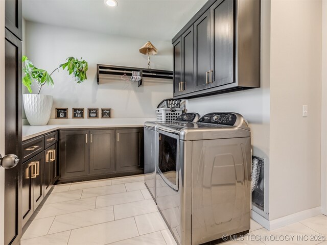 laundry room featuring washing machine and dryer, light tile patterned floors, and cabinets