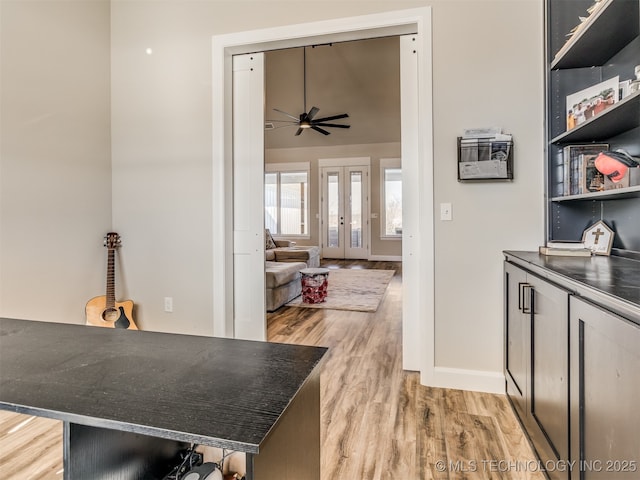 interior space with kitchen peninsula, french doors, light wood-type flooring, ceiling fan, and a kitchen breakfast bar