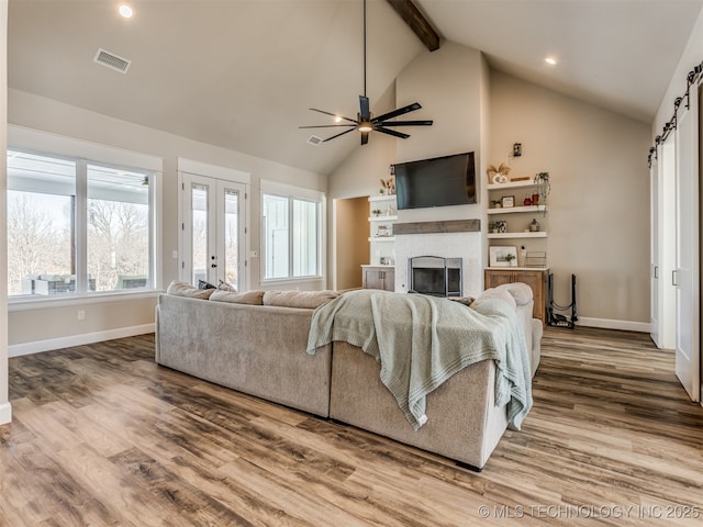 living room featuring hardwood / wood-style floors, a barn door, vaulted ceiling with beams, ceiling fan, and french doors