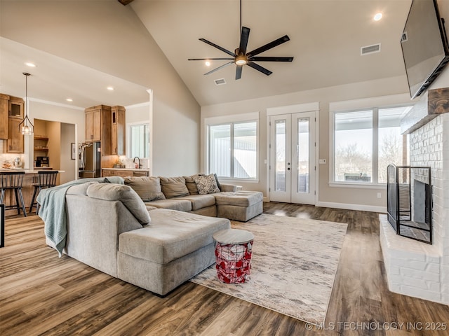 living room featuring wood-type flooring, a fireplace, ceiling fan, and a wealth of natural light