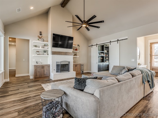 living room with a fireplace, ceiling fan, a barn door, and wood-type flooring