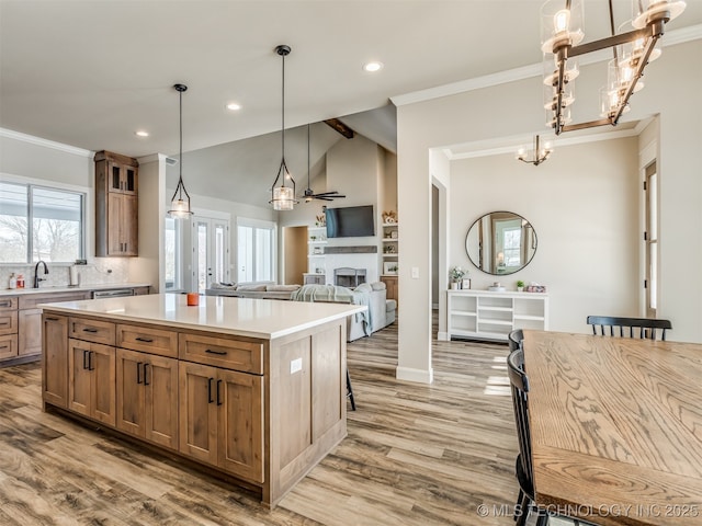 kitchen with a kitchen island, light wood-type flooring, decorative light fixtures, and lofted ceiling