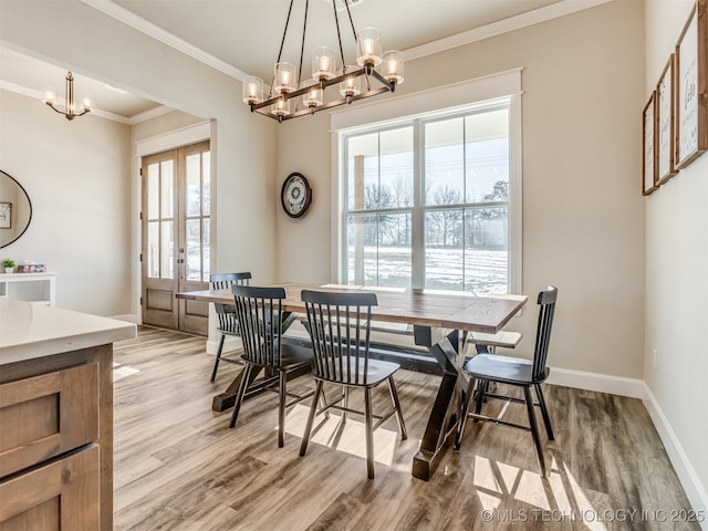 dining space featuring french doors, an inviting chandelier, crown molding, and light hardwood / wood-style flooring