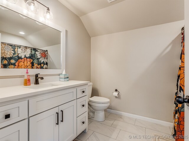 bathroom featuring toilet, vanity, and vaulted ceiling