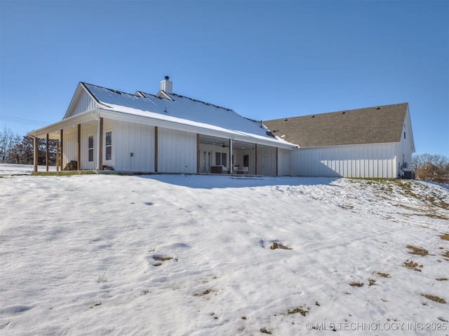 snow covered house with covered porch and central air condition unit