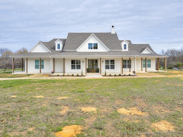 modern farmhouse style home featuring a chimney, a front yard, board and batten siding, covered porch, and a shingled roof