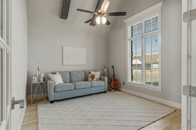 living room featuring lofted ceiling with beams, ceiling fan, and light wood-type flooring