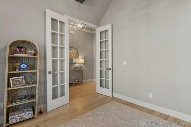 entryway featuring french doors, vaulted ceiling, hardwood / wood-style flooring, built in shelves, and a chandelier