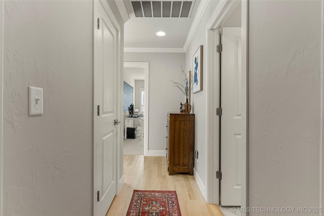 corridor with light wood-type flooring and ornamental molding