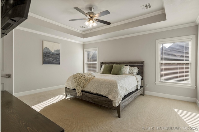 carpeted bedroom with a tray ceiling, ceiling fan, and ornamental molding