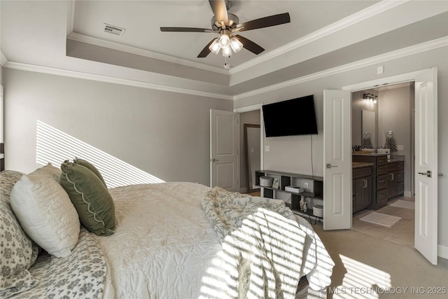 bedroom with light carpet, ensuite bathroom, ceiling fan, ornamental molding, and a tray ceiling