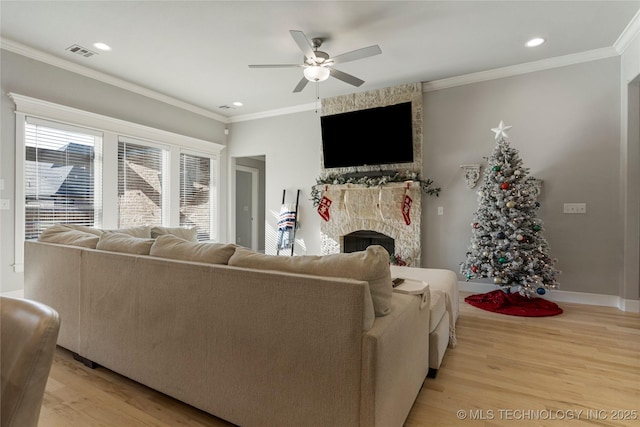 living room with ceiling fan, ornamental molding, a fireplace, and light hardwood / wood-style flooring