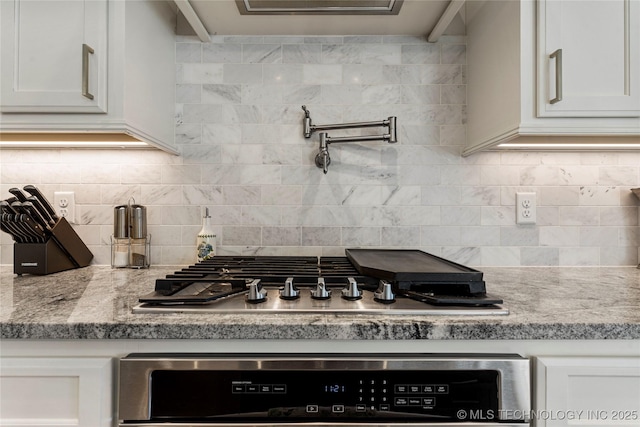 kitchen featuring light stone countertops, decorative backsplash, and white cabinetry