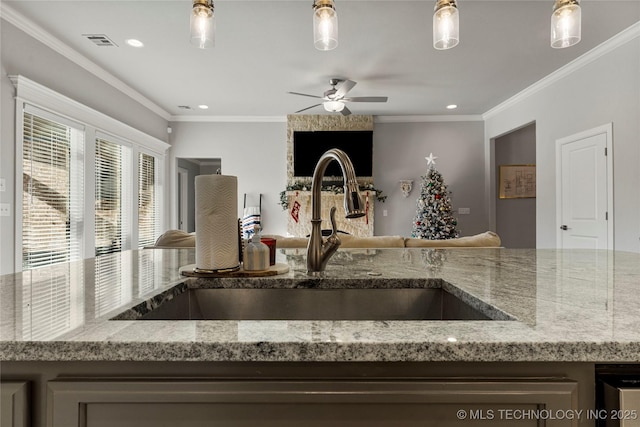 kitchen featuring ceiling fan, sink, light stone counters, and ornamental molding