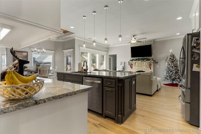 kitchen featuring sink, stainless steel appliances, pendant lighting, a kitchen island with sink, and dark brown cabinets