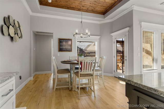 dining area with light hardwood / wood-style floors, a raised ceiling, and an inviting chandelier