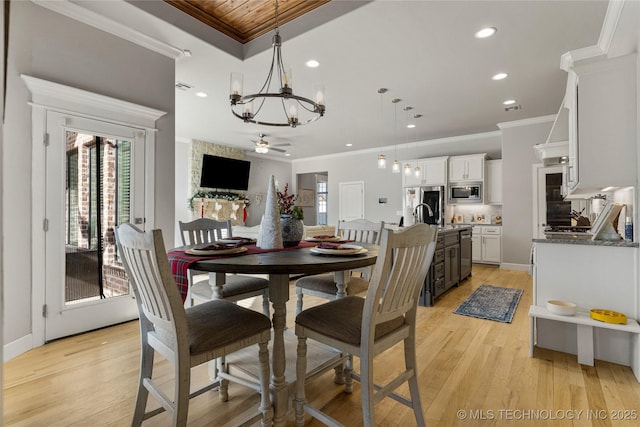 dining area with ceiling fan with notable chandelier, light hardwood / wood-style floors, and ornamental molding