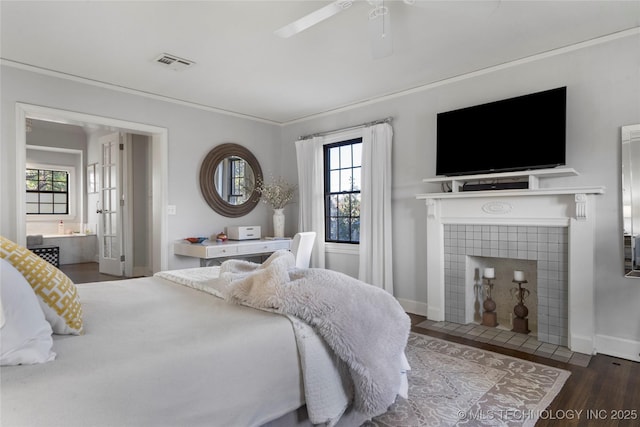 bedroom featuring ceiling fan, dark hardwood / wood-style flooring, connected bathroom, and a tiled fireplace