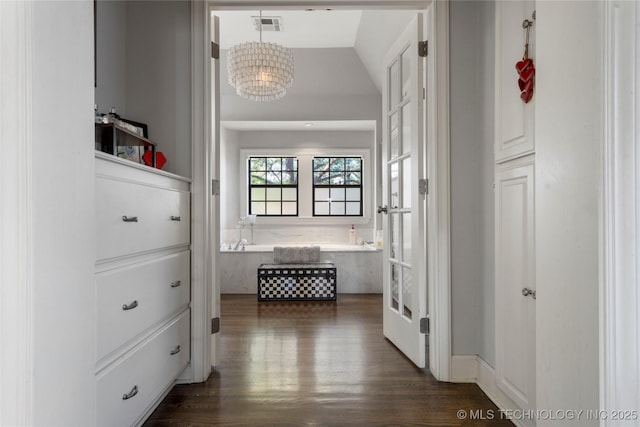 corridor with a notable chandelier, lofted ceiling, and dark hardwood / wood-style floors