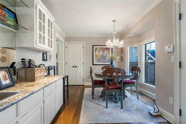 dining room with dark wood-type flooring, ornamental molding, and a chandelier