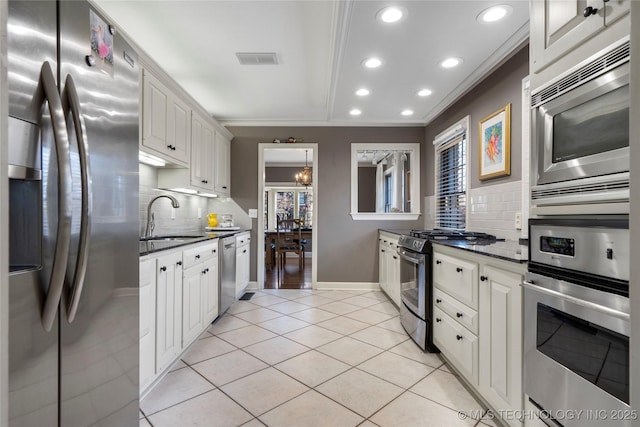 kitchen with decorative backsplash, crown molding, white cabinets, appliances with stainless steel finishes, and sink