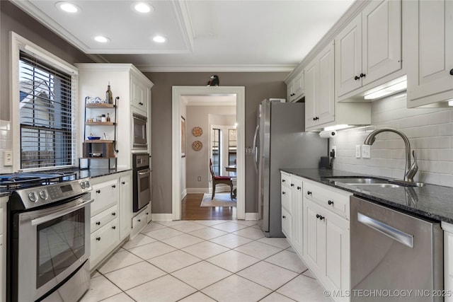 kitchen featuring appliances with stainless steel finishes, white cabinetry, light tile patterned flooring, and sink