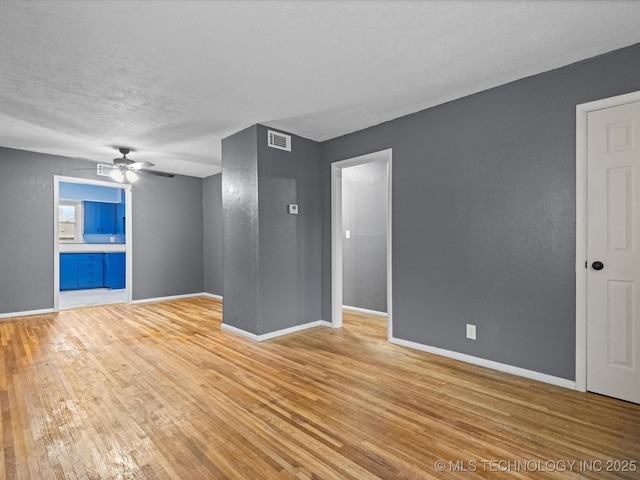 unfurnished living room featuring ceiling fan, light wood-type flooring, and a textured ceiling