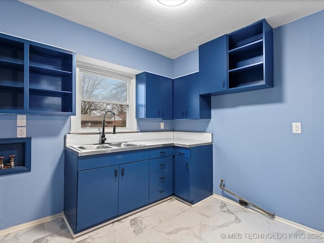 kitchen featuring a textured ceiling, blue cabinets, and sink