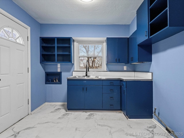 kitchen featuring blue cabinetry, a textured ceiling, a healthy amount of sunlight, and sink