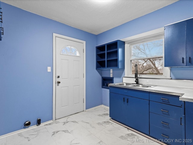 clothes washing area featuring cabinets, a textured ceiling, and sink