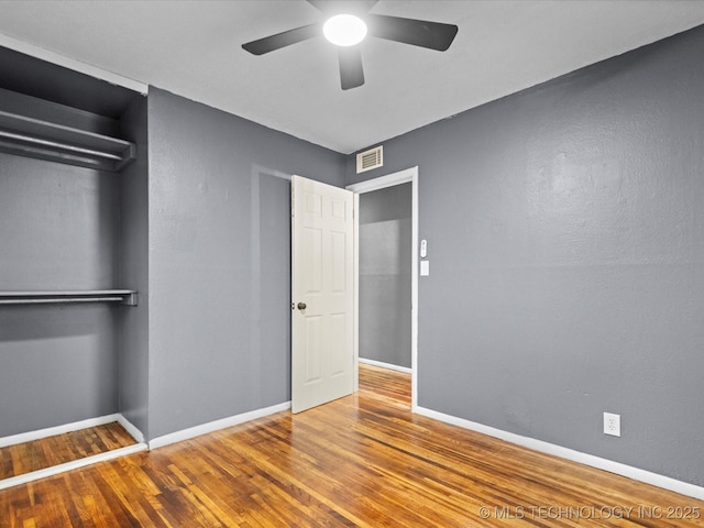 unfurnished bedroom featuring ceiling fan, a closet, and hardwood / wood-style flooring