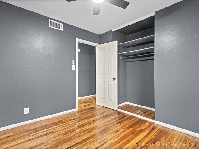 unfurnished bedroom featuring hardwood / wood-style flooring, ceiling fan, and a closet