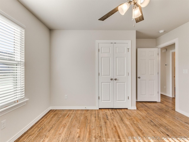 unfurnished bedroom with ceiling fan, light wood-type flooring, and a closet