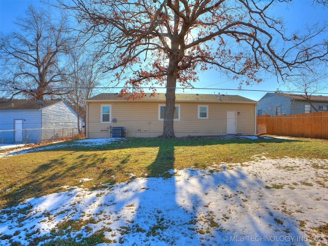 snow covered property featuring a lawn and central AC unit