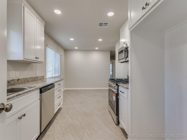 kitchen featuring sink, white cabinetry, light stone counters, and appliances with stainless steel finishes