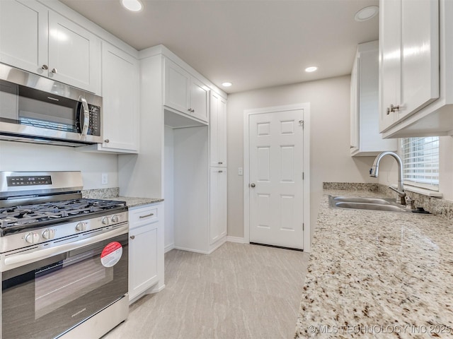 kitchen featuring sink, white cabinetry, light stone counters, and appliances with stainless steel finishes