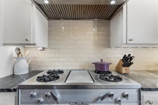 kitchen featuring wall chimney exhaust hood, stove, decorative backsplash, and white cabinets