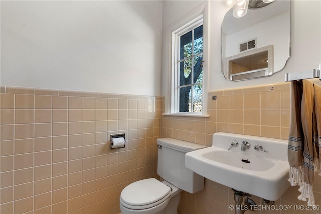 bathroom featuring tile walls, sink, and toilet