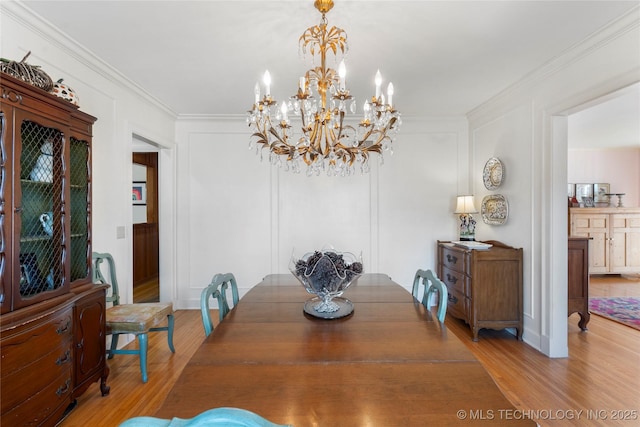 dining space with crown molding, a chandelier, and light hardwood / wood-style flooring