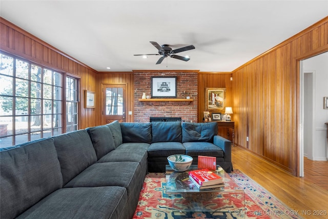 living room with crown molding, a brick fireplace, hardwood / wood-style floors, and wooden walls